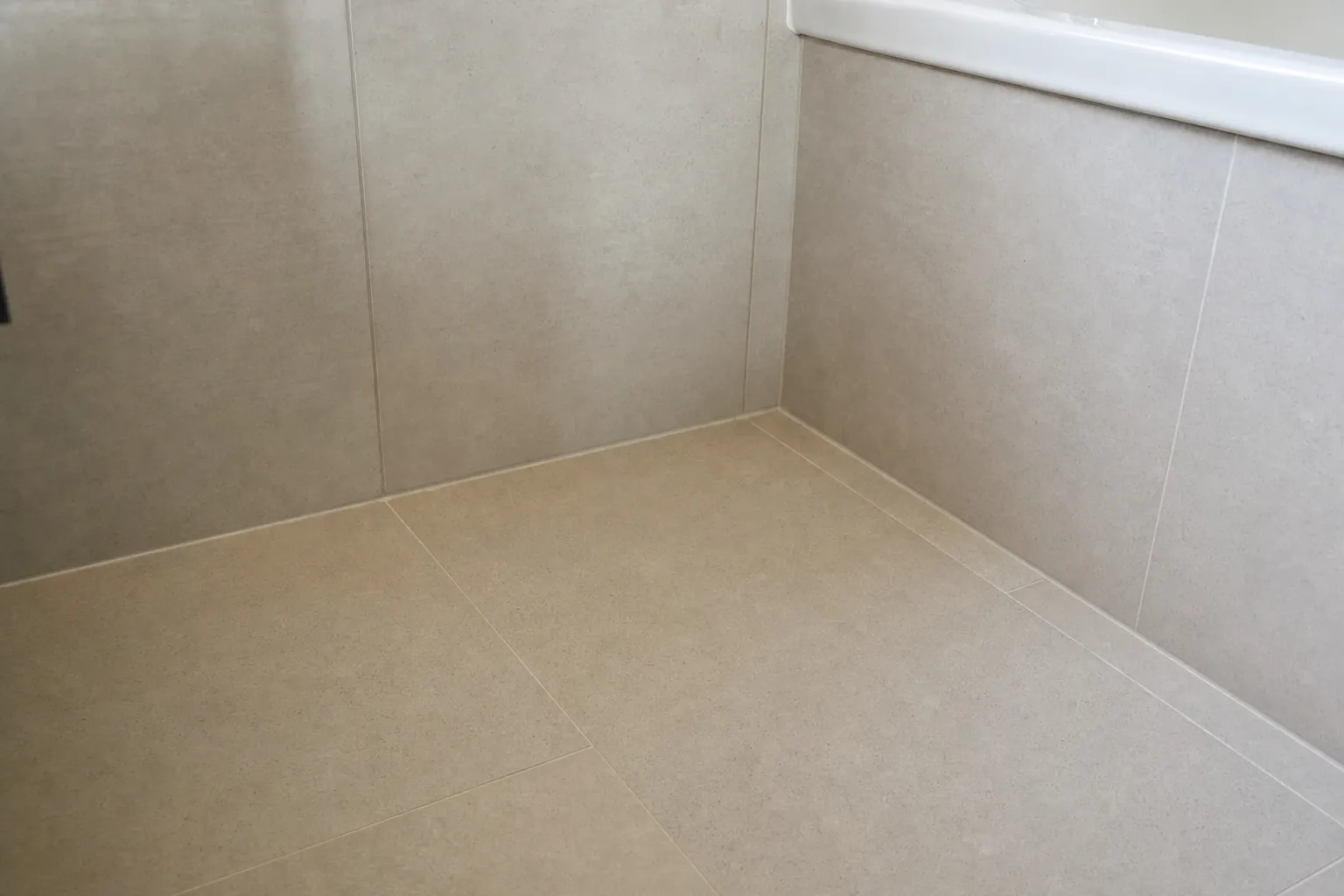 Großformatige matte Fliesen in Steinoptik an Wand und Boden mit schmalen Fugen im Badezimmer (computergeneriertes Symbolbild)