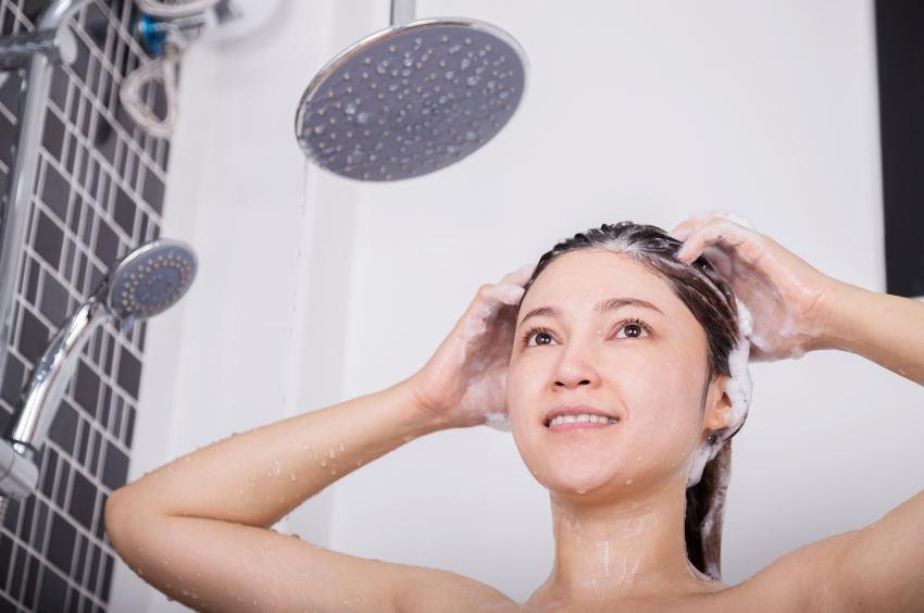 Frau unter Regendusche Frau wäscht Haare